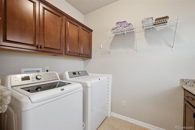 laundry area featuring separate washer and dryer, cabinet space, baseboards, and light tile patterned flooring