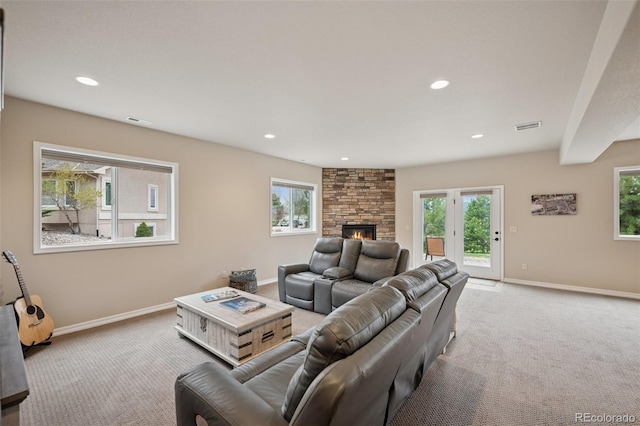 carpeted living room featuring baseboards, a stone fireplace, plenty of natural light, and recessed lighting