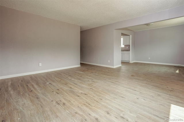 spare room featuring light hardwood / wood-style floors and a textured ceiling