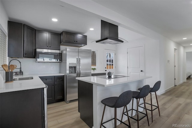 kitchen with appliances with stainless steel finishes, light wood-type flooring, ventilation hood, sink, and a kitchen island