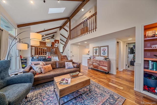 living room with beam ceiling, a skylight, high vaulted ceiling, and light wood-type flooring