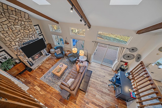 living room with rail lighting, light hardwood / wood-style floors, beam ceiling, and a skylight