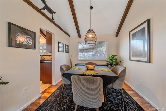 dining space featuring vaulted ceiling with beams, light hardwood / wood-style floors, and a wealth of natural light