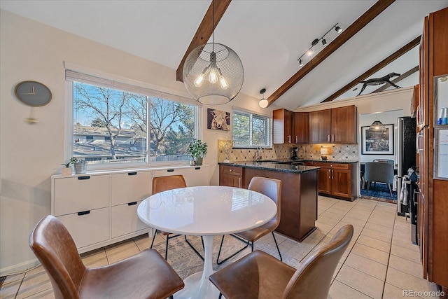 tiled dining space with sink and lofted ceiling with beams