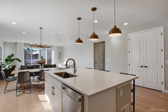 kitchen featuring pendant lighting, sink, dishwasher, a kitchen island with sink, and white cabinets