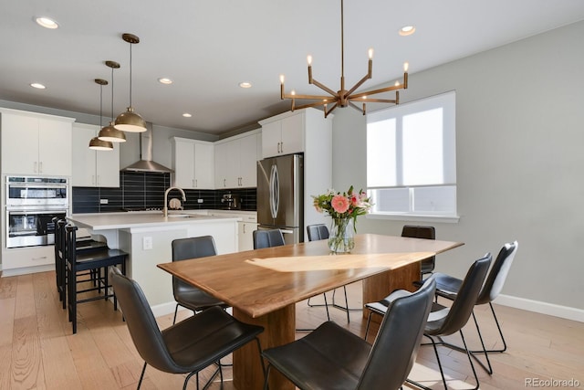 kitchen with white cabinetry, stainless steel appliances, an island with sink, decorative light fixtures, and wall chimney exhaust hood