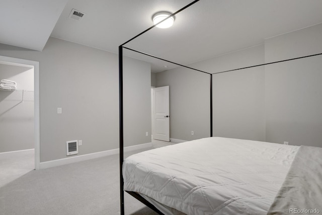 bedroom featuring light colored carpet, a closet, and a walk in closet