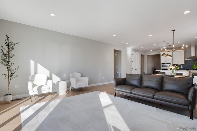 living room featuring baseboards, recessed lighting, and a chandelier