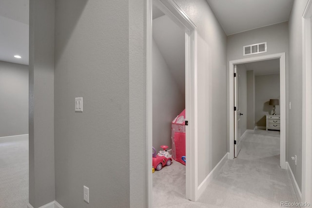 corridor with baseboards, light colored carpet, and visible vents