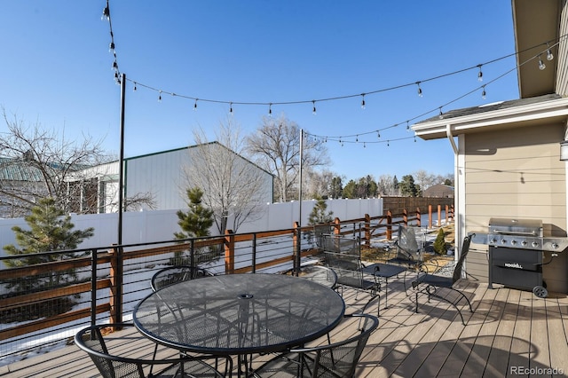 wooden deck with grilling area, a fenced backyard, and outdoor dining space