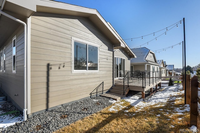 view of snow covered exterior with a residential view and a wooden deck