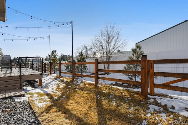 snowy yard featuring fence and a deck