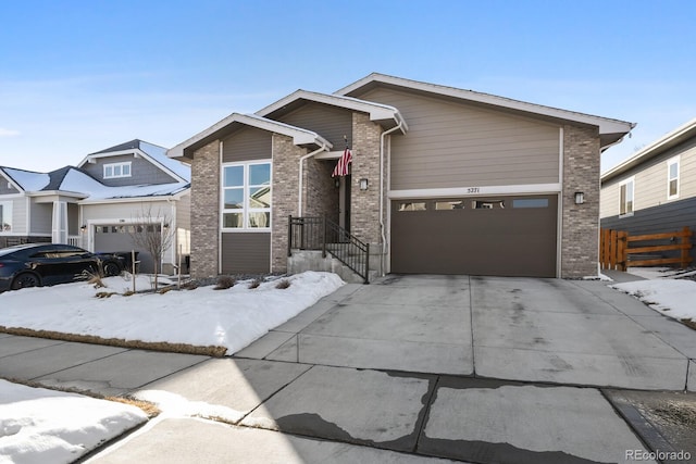 view of front of house featuring brick siding, a garage, fence, and driveway