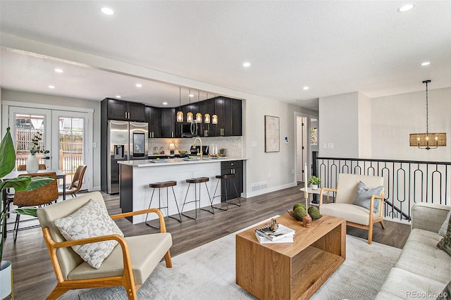 6775 Newland St, Arvada, CO 80003 - living room with light wood-type flooring, plenty of natural light, recessed lighting, a chandelier, and baseboards