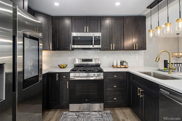 6775 Newland St, Arvada, CO 80003 - kitchen with appliances with stainless steel finishes, a sink, dark wood finished floors, light countertops, and recessed lighting