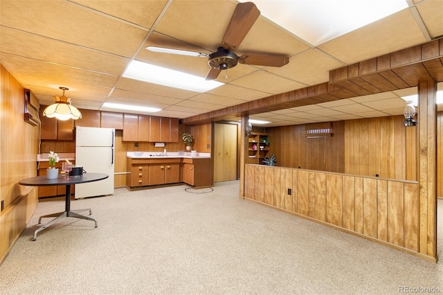9100 Yucca Way, Thornton, CO 80229 - kitchen with freestanding refrigerator, wooden walls, brown cabinetry, and a drop ceiling