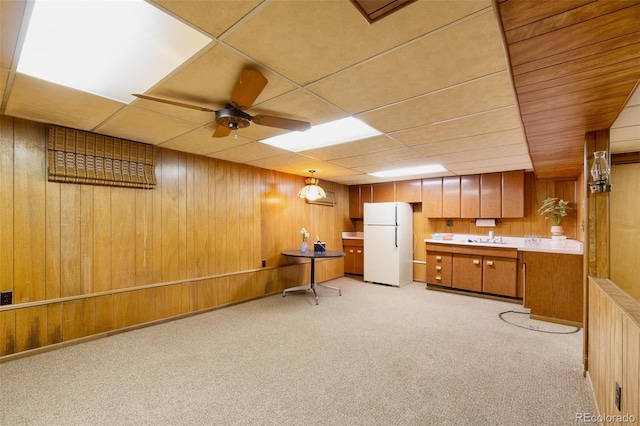 9100 Yucca Way, Thornton, CO 80229 - kitchen featuring freestanding refrigerator, wood walls, light colored carpet, and brown cabinets