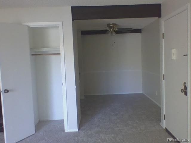 unfurnished bedroom with dark carpet, a closet, and ceiling fan