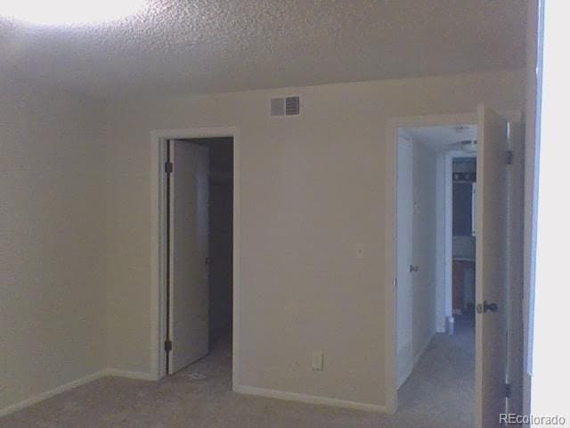 carpeted spare room with a textured ceiling