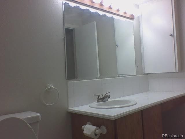 bathroom featuring vanity, toilet, and tasteful backsplash