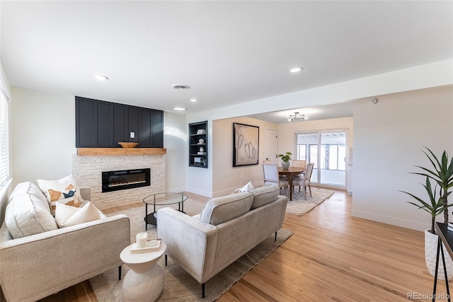 living room with a fireplace, light wood finished floors, recessed lighting, visible vents, and baseboards