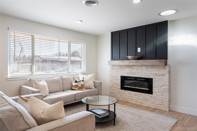 living room with recessed lighting, a fireplace, visible vents, baseboards, and light wood-style floors