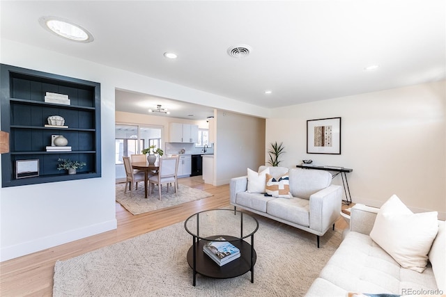 living room with light wood-style floors, recessed lighting, visible vents, and baseboards