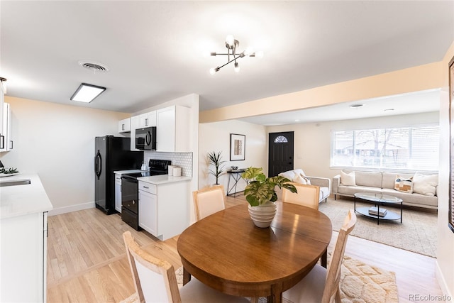 dining room with light wood-style flooring, visible vents, and baseboards