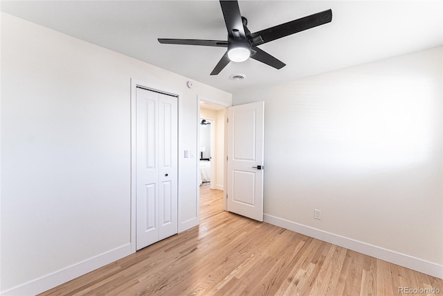 unfurnished bedroom featuring light wood-type flooring, a closet, visible vents, and baseboards