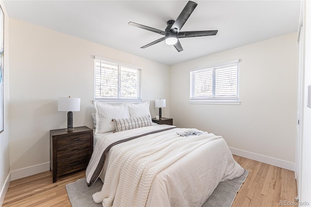 bedroom featuring light wood-type flooring, multiple windows, and baseboards