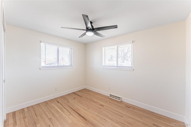 unfurnished room featuring a wealth of natural light, visible vents, and baseboards