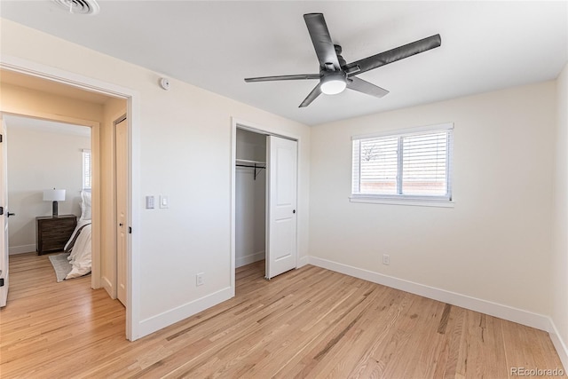 unfurnished bedroom with light wood-type flooring, a closet, ceiling fan, and baseboards