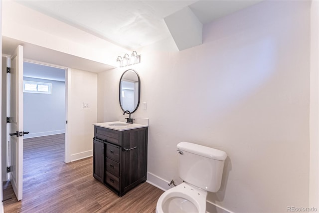 bathroom featuring toilet, baseboards, wood finished floors, and vanity