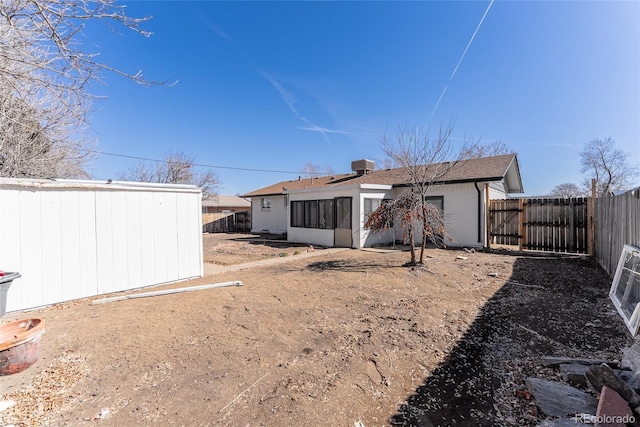 rear view of house with an outdoor structure, a fenced backyard, and a sunroom