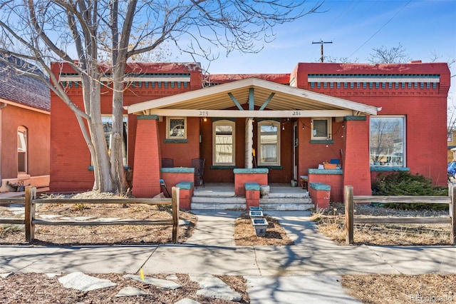 view of front of home featuring a porch, fence, and brick siding