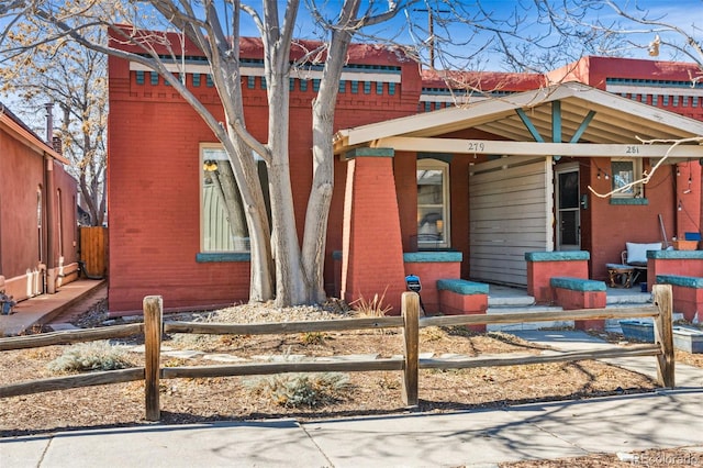 view of front of property featuring covered porch, brick siding, and fence