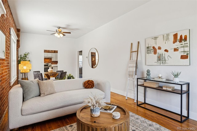 living room with brick wall, plenty of natural light, and wood finished floors