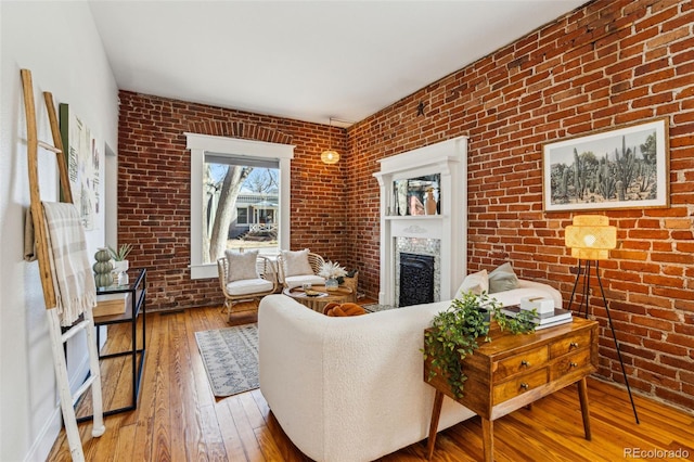 living area featuring brick wall, a fireplace, and hardwood / wood-style floors