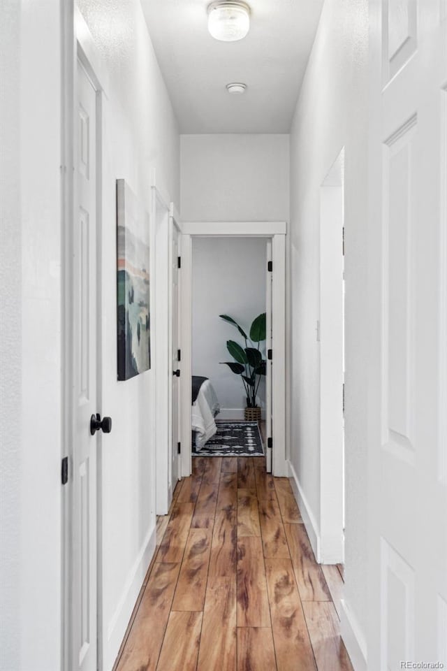 hallway featuring baseboards and light wood finished floors