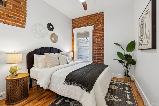 bedroom with ceiling fan, wood finished floors, and baseboards