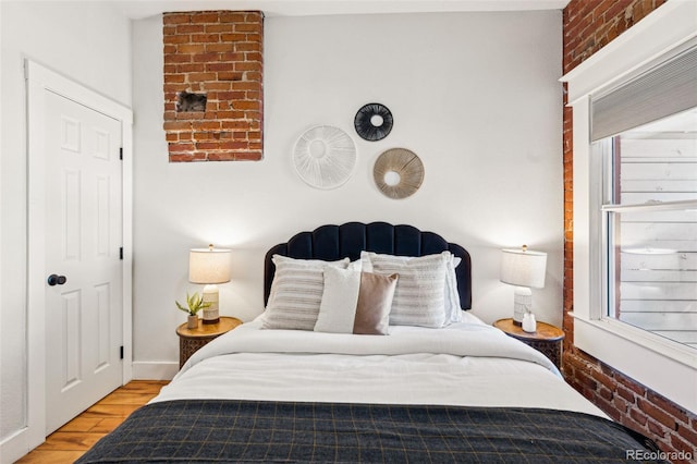 bedroom featuring brick wall and wood finished floors