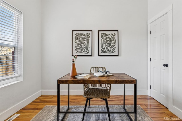 home office with visible vents, light wood-style flooring, and baseboards