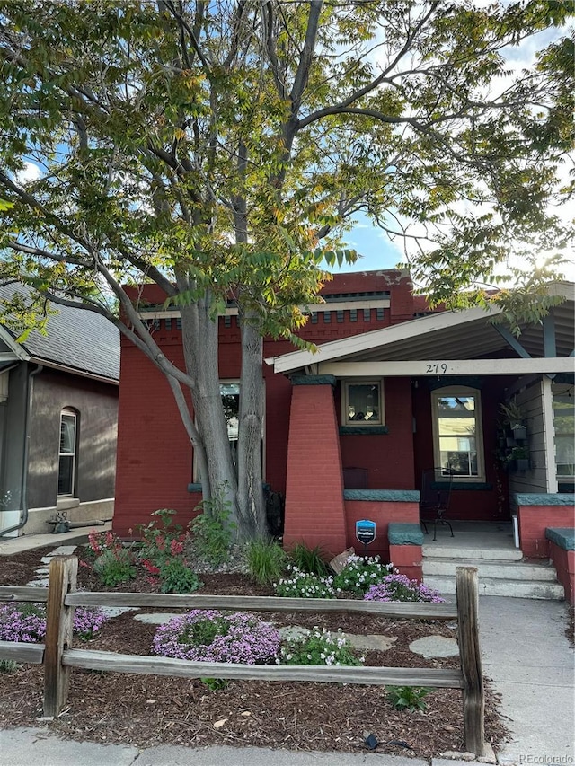 view of front of home featuring a porch, a fenced front yard, and brick siding