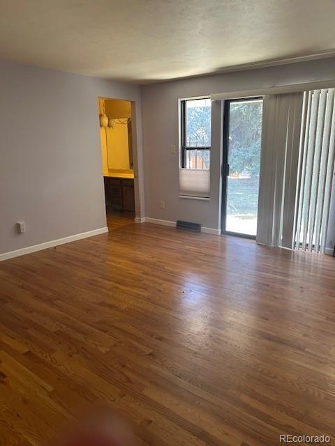 spare room with dark wood-type flooring and baseboards