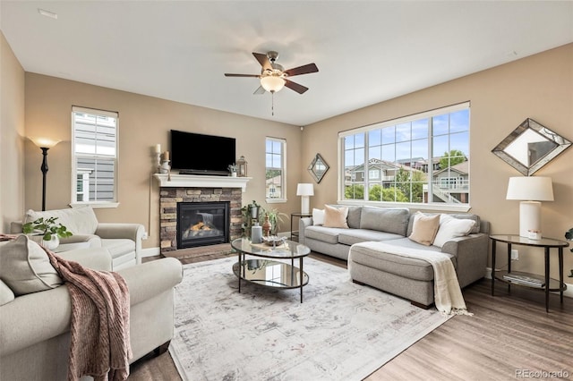 3319 Starry Night Loop, Castle Rock, CO 80109 - living area featuring wood finished floors, a ceiling fan, a stone fireplace, and baseboards
