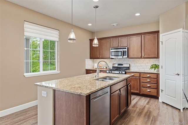 3319 Starry Night Loop, Castle Rock, CO 80109 - kitchen with stainless steel appliances, a sink, light wood-style floors, decorative backsplash, and light stone counters