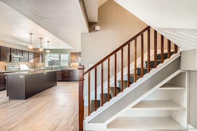 staircase with a textured ceiling and hardwood / wood-style floors