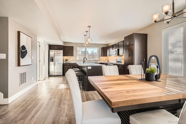 dining space with sink, a chandelier, and light wood-type flooring