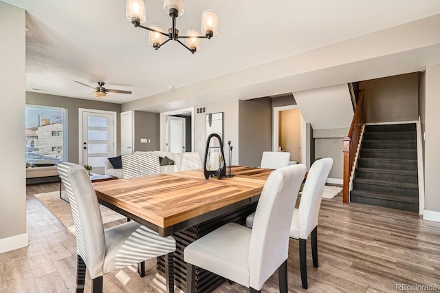 dining area featuring a textured ceiling, hardwood / wood-style floors, and ceiling fan with notable chandelier