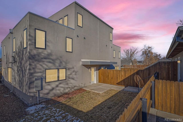 back house at dusk featuring a patio